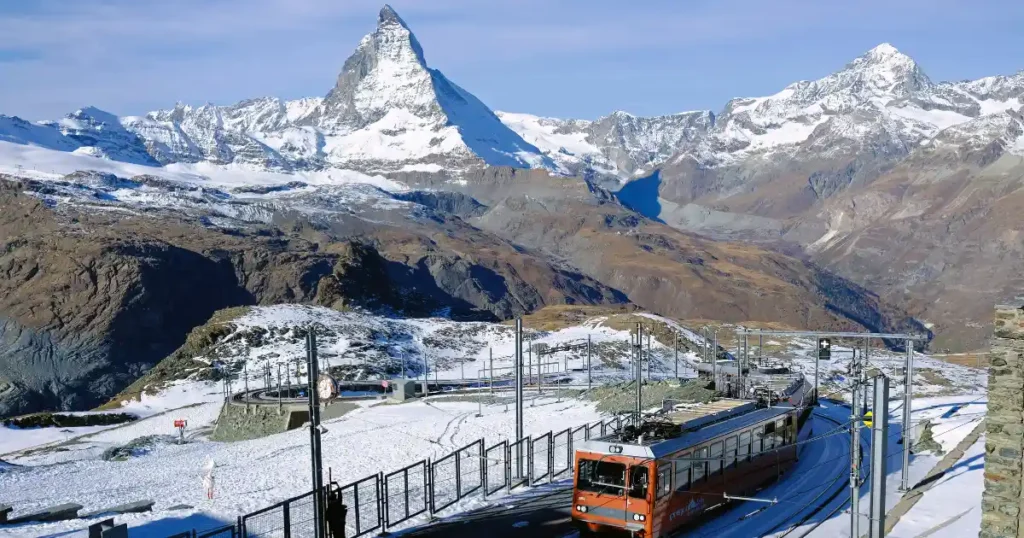 The snow-capped Matterhorn and a scenic train in Switzerland, one of the best places to travel to in december for breathtaking alpine views.