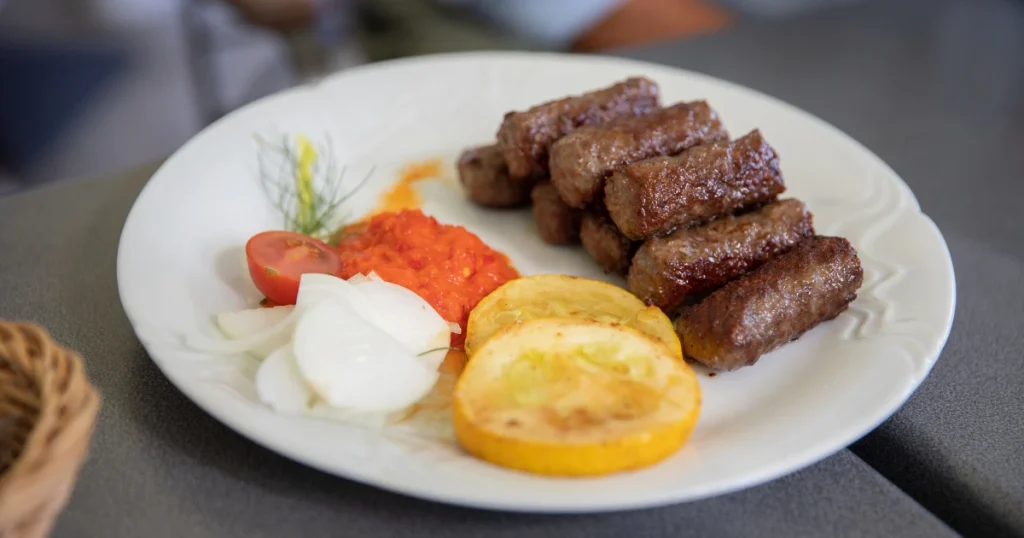 A traditional plate of cevapi and local food to try when you travel the balkans cheaply.